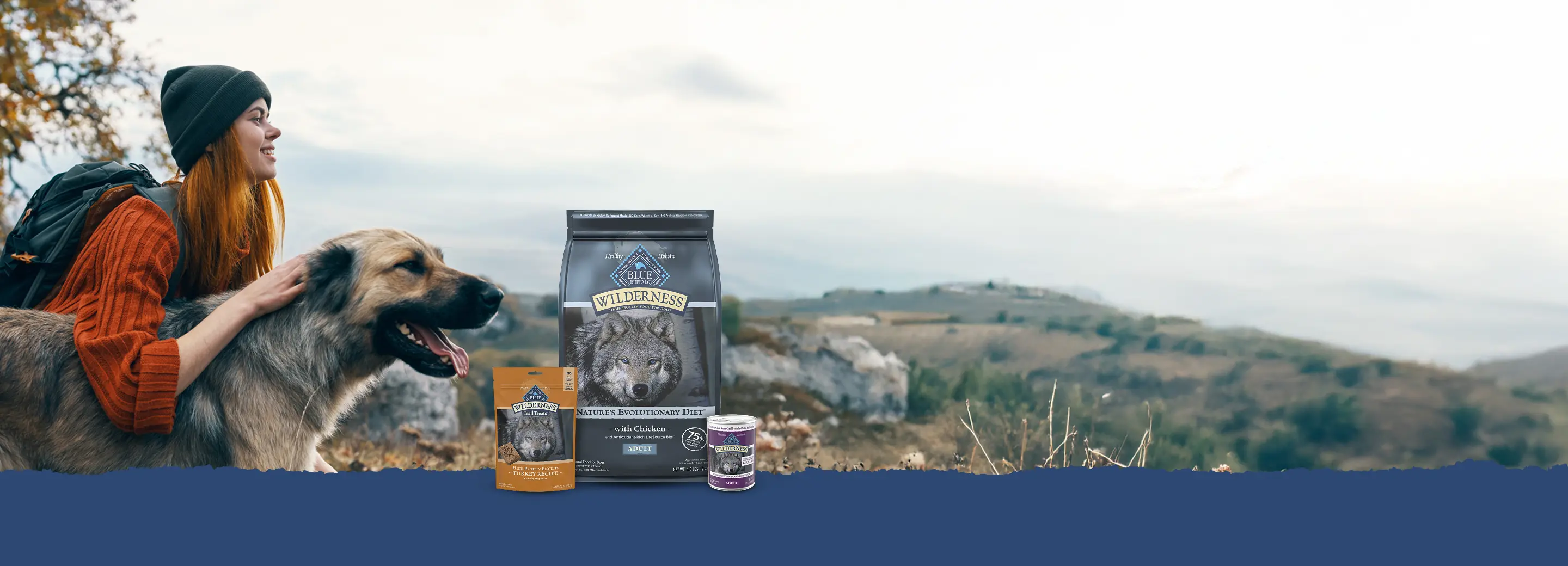 A woman in a beanie and her dog are enjoying the view on a hike.